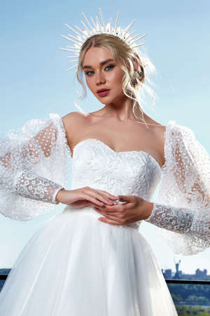 Beautiful tender young woman sexy brunette bride in a luxury white wedding dress lace chiffon Summer happiness awaits the groom before the wedding ceremony makeup accessory jewelry smile.の写真素材