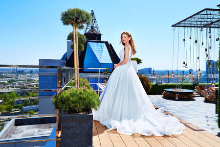 Beautiful tender young woman sexy brunette bride in a luxury white wedding dress lace chiffon Summer happiness awaits the groom before the wedding ceremony makeup accessory jewelry smile.の写真素材