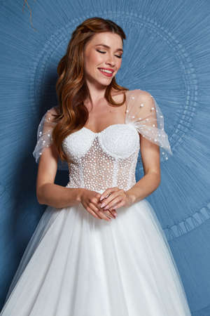 Beautiful tender young woman sexy brunette bride in a luxury white wedding dress lace chiffon Summer happiness awaits the groom before the wedding ceremony makeup accessory jewelry smile.の写真素材