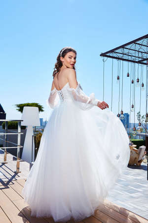 Beautiful woman bride fashion model brunette hair bright makeup pretty wear long silk white dress with lace bridal ceremony wedding espousal in blooming romance garden party marriage happy big day.の写真素材