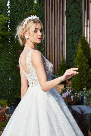 Sexy beautiful blonde woman pretty bride wedding big day marriage ceremony in summer garden wearing long silk and lace white dress bright makeup hairstyle pure love interior.の写真素材