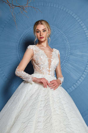 Beautiful tender young woman sexy blond bride in a luxury white wedding dress lace chiffon Summer happiness awaits the groom before the wedding ceremony makeup accessory jewelry smile.の写真素材