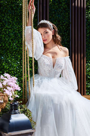 Beautiful tender young woman sexy brunette bride in a luxury white wedding dress lace chiffon Summer happiness awaits the groom before the wedding ceremony makeup accessory jewelry smile.の写真素材