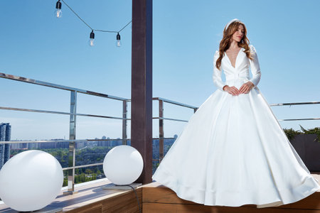 Beautiful tender young woman sexy brunette bride in a luxury white wedding dress lace chiffon Summer happiness awaits the groom before the wedding ceremony makeup accessory jewelry smile.の写真素材