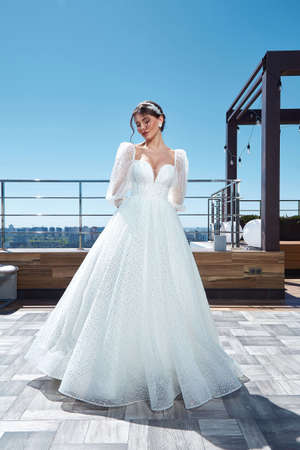 Beautiful woman bride fashion model brunette hair bright makeup pretty wear long silk white dress with lace bridal ceremony wedding espousal in blooming romance garden party marriage happy big day.の写真素材