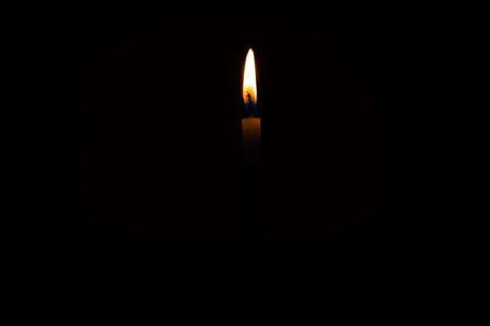 Close up single burning, bright white paraffin candle light on isolated dark black background. Red, orange, yellow candle fire flame smoke in party festival celebration at night. Copy space for text.の写真素材
