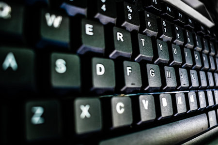Close up macro image of keys of black computer keyboard on table. White color alphabet letters...