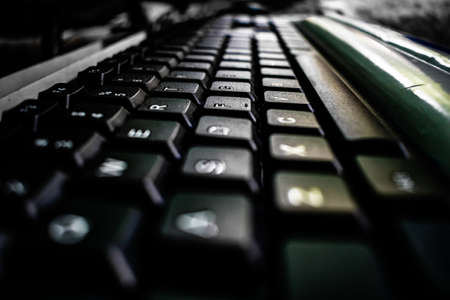 Close up macro image of keys of black computer keyboard on table. White color alphabet letters printed on black large square key for typing. It is an important input device to write word, text, blog.の写真素材