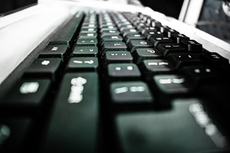 Close up macro image of keys of black computer keyboard on table. White color alphabet letters...