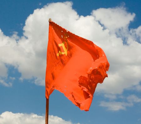 Torn, dirty, old Soviet red flag against the backdrop of the sky.の写真素材