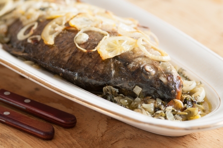 Oven baked carp fish with onions and lemonの写真素材