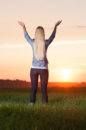 Blonde woman lifts hands up to the sunの写真素材