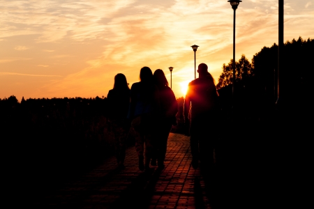 A group of young people walking to sunset in city parkの写真素材