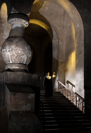 Nun on stairs of nunnery holding candle lampの写真素材