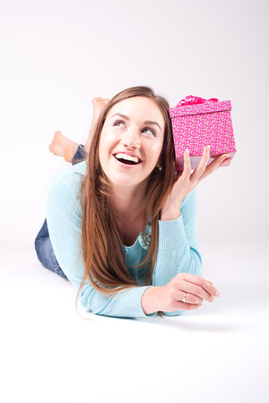 Beautiful woman wonders what is inside the giftの写真素材
