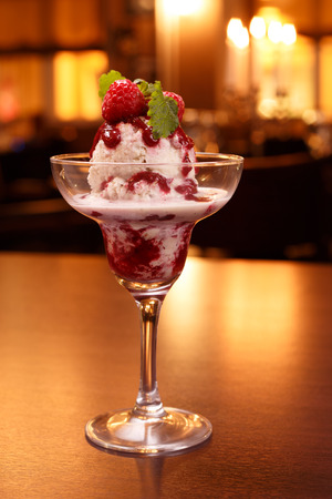 Ice cream dessert with berry sauce in restaurantの写真素材