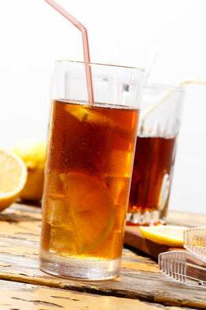 Glass of cold ice tea with lemon, condensate on glass, bright backgroundの写真素材