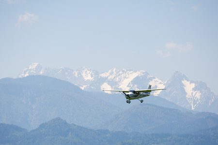 Small airplane flying, mountains on backgroundの写真素材