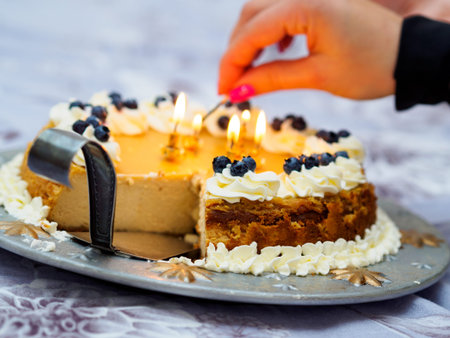 Woman lights candles on birthday cake