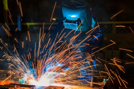 Welders team welding automotive part at assembly line in car factory