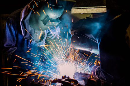 Industrial worker is welding metal in factory