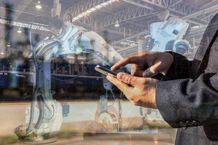 businessman is used smart phone control automate wireless Robot welding. It is industrial4.0 concept...