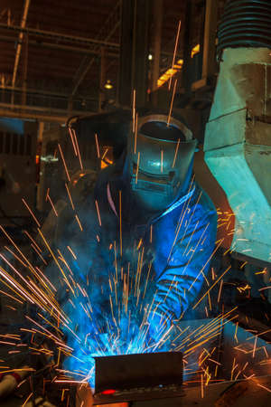 welder is welding assembly car parts in factory with protection maskの写真素材