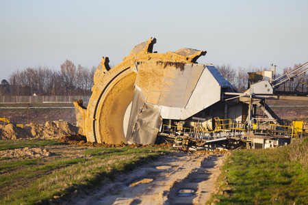 A giant Bucket Wheel Excavator at work in a lignite pit mine with a dirt road leading to it in the foregroundのeditorial素材