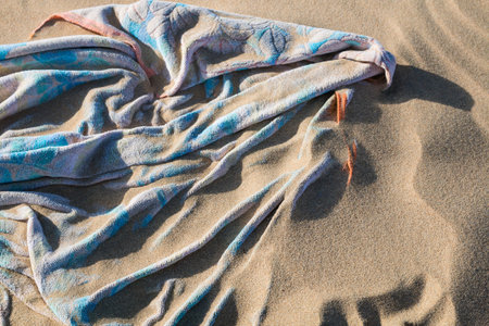 A beach towel covered by flying sand at Playas de Sotavento, Fuerteventuraの写真素材