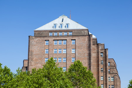 A harbor building in Hamburg, Germany behind some trees near the Chilehaus.のeditorial素材