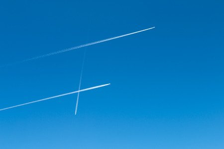 Three jet trails with two parellel trails and one plane crossingの写真素材