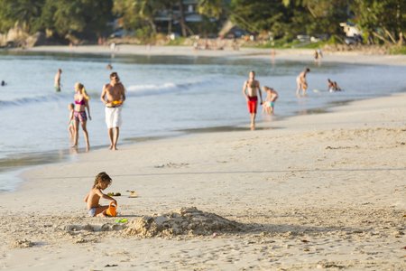 MAHE - AUGUST 08: A child playing in the sand at Beau Vallon Beach in the west of Mahe, Seychelles with other tourists in the background on August 08, 2014のeditorial素材