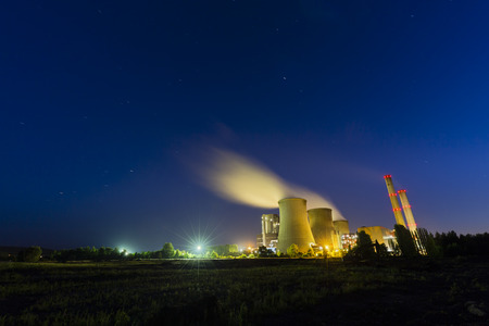 A large coal-fired power plant at night with a lot of steam and deep blue sky with some star trails.のeditorial素材