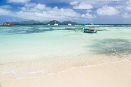 A little blue boat in a lagoon in La Digue, Seychelles with view to Praslinの写真素材