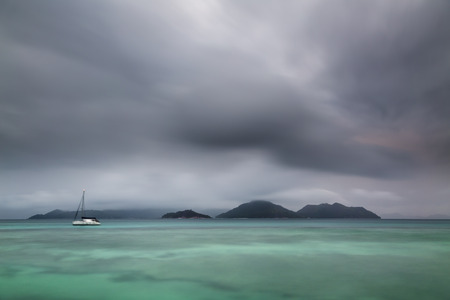 View from La Digue to Praslin at sunset under heavy clouds, Seychelles.の写真素材