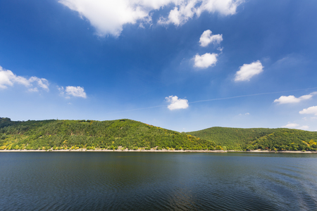 Shore and hills around Lake Rursee with perfect blue sky and sunlight in summer seen from a boat.の写真素材