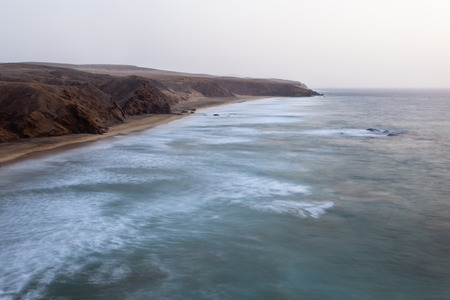 Beach and rocky coastline at La Pared, Fuerteventura during a slight sandstorm. Long exposure evening shot.の写真素材