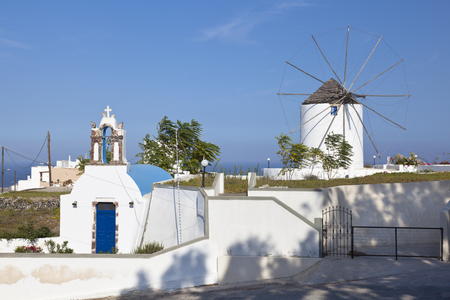 A windmill and a chapel in the center of Santorini with blue sky.のeditorial素材