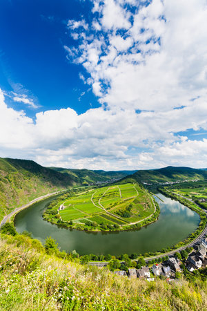 View of a riverbend of the Moselle River in the Eifel village of Bremm in Germany in summer. Lakes from the Calmont vineyards with blue sky.の写真素材