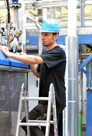 operator repairs a machine in an industrial plant with toolsの写真素材