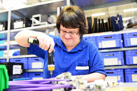 older woman assembles electronic components in a hi tech factoryの写真素材