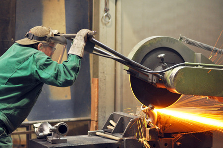 Workers in a foundry grind castings with a grinding machine - Heavy industry workplaceの写真素材