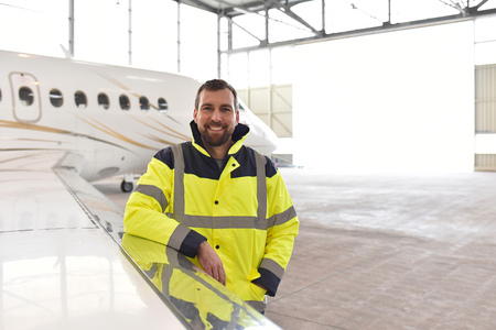 Portrait of an aircraft mechanic in a hangar with jets at the airport - Checking the aircraft for safety and technical functionの写真素材