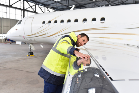 Aircraft mechanic inspects and checks the technology of a jet in a hangar at the airportの写真素材