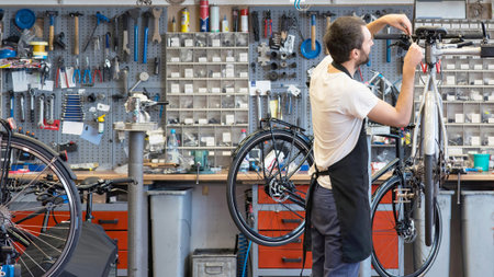 friendly and competent bicycle mechanic in a workshop repairs a bikeの写真素材
