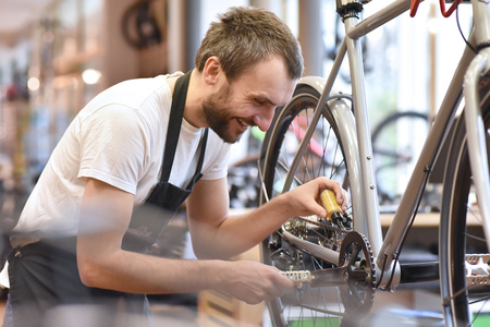 mechanic in a bicycle repair shop oiling the chain of a bikeの写真素材
