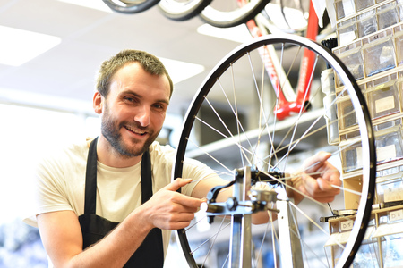 friendly and competent bicycle mechanic in a workshop repairs a bikeの写真素材