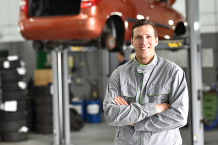 portrait worker / mechanic in a garage - smiling man in workwearの写真素材
