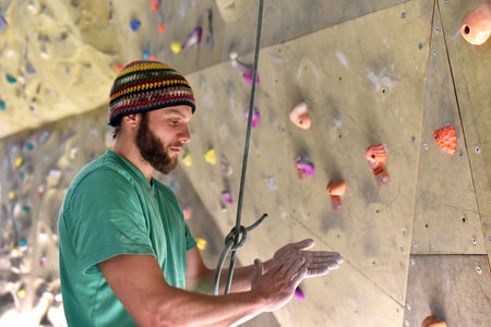 sportsman in a boulder hall rubs his hands with chalk, preparation climbing sport