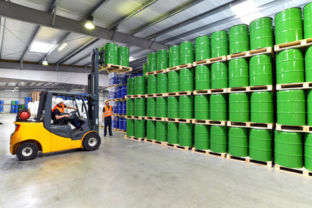 group of workers in the logistics industry work in a warehouse with chemicals - lifting truck